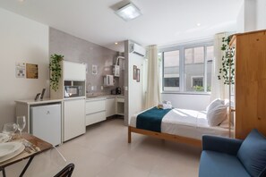A compact room with a bed, a small kitchenette, a dining area, and a window with curtains. - 5 minutes from Copacabana beach | BI202 (Rio de Janeiro)