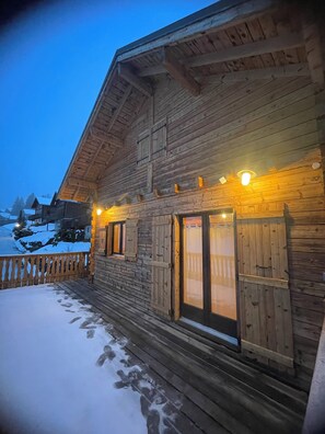 Una cabana de fusta amb un balcó i terra coberta de neu.