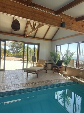 Un espace aménagé au bord de la piscine, avec un fauteuil de relaxation, une petite table et une plante en pot.