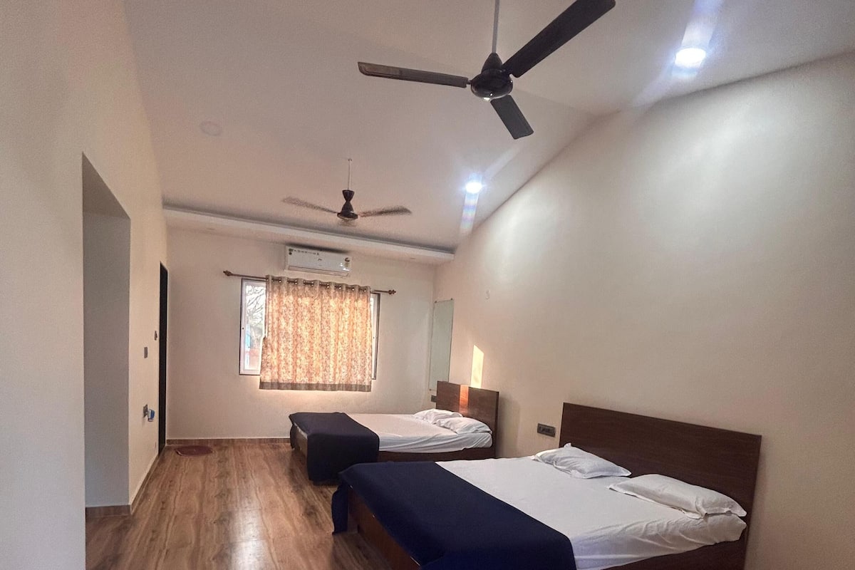 Une chambre avec deux lits, un ventilateur de plafond et une fenêtre avec des rideaux.