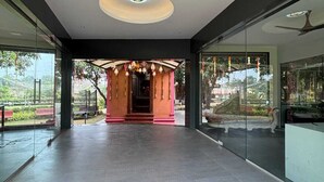 A modern hotel lobby with a central decorative archway, large glass windows, and a ceiling with recessed lighting. - Glory of MJ, Family Resort in Nature, Panvel (Panvel)