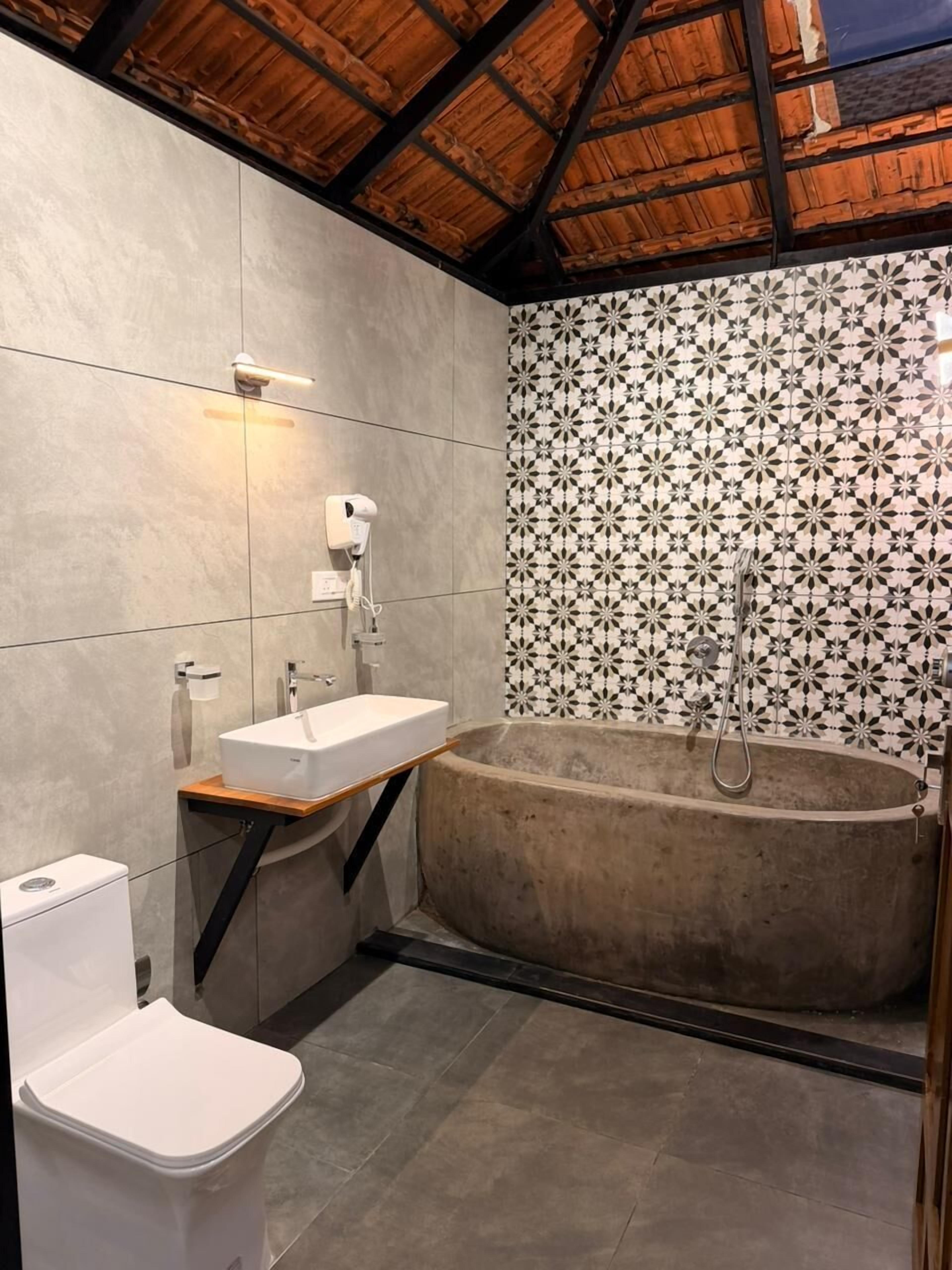 Une salle de bain avec une baignoire, un lavabo, des toilettes et un mur décoré d’un motif.