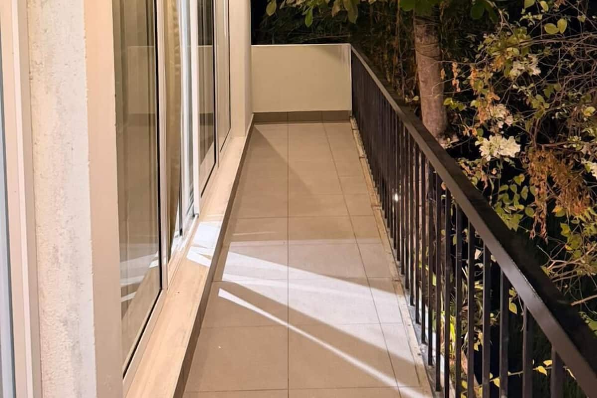 A covered balcony with a tiled floor, glass doors, and a wooden ceiling.