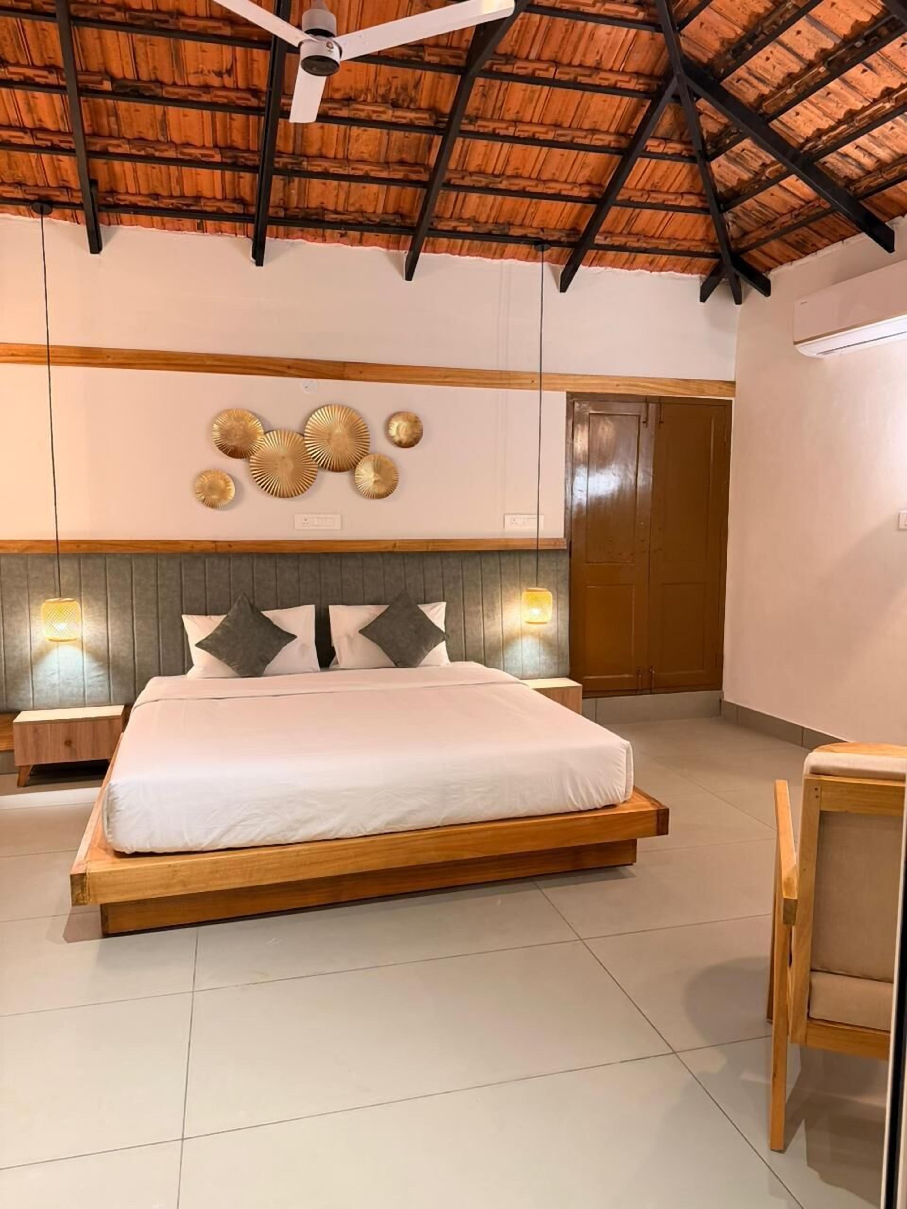 Un dormitorio con cama, ventilador de techo, apliques de pared y una puerta.