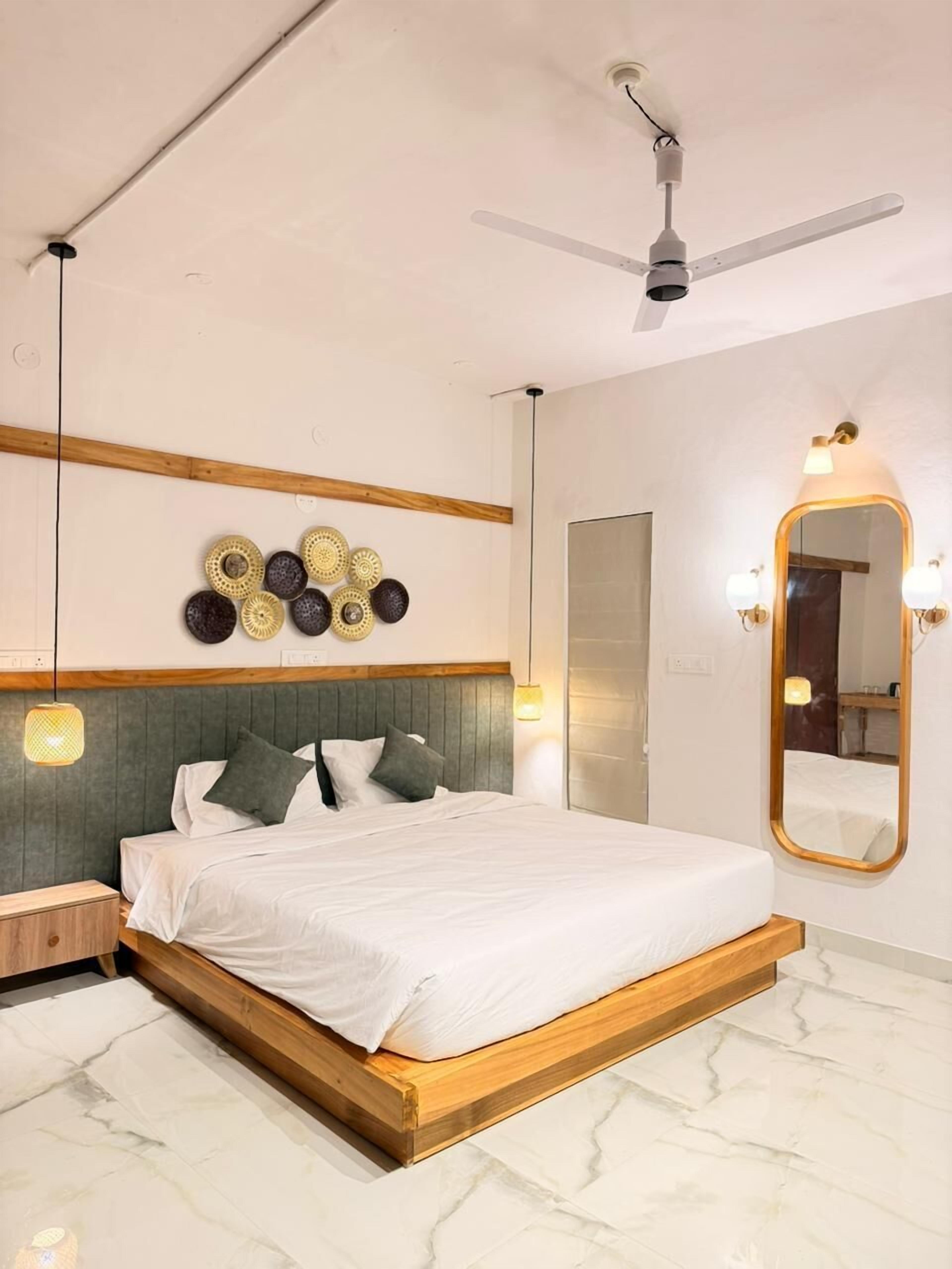 A bedroom with a bed, a ceiling fan, a wall-mounted mirror, and decorative plates.