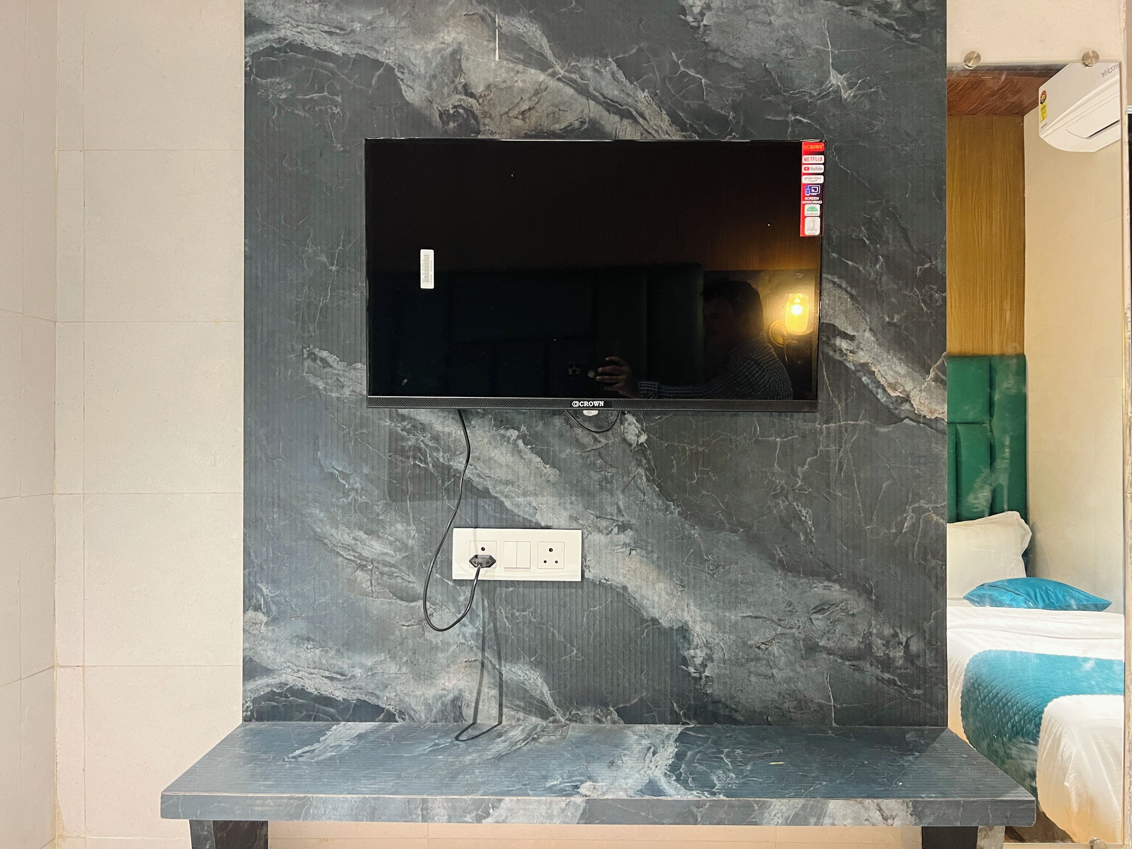 Een flatscreen televisie bevestigd aan een marmeren muur, met een stopcontact eronder.
