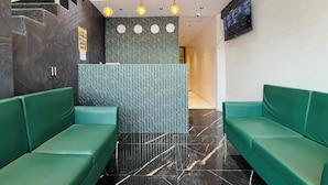 A reception area with green seating, a patterned wall, and a staircase. - Hotel Imperial Suite (Mumbai)
