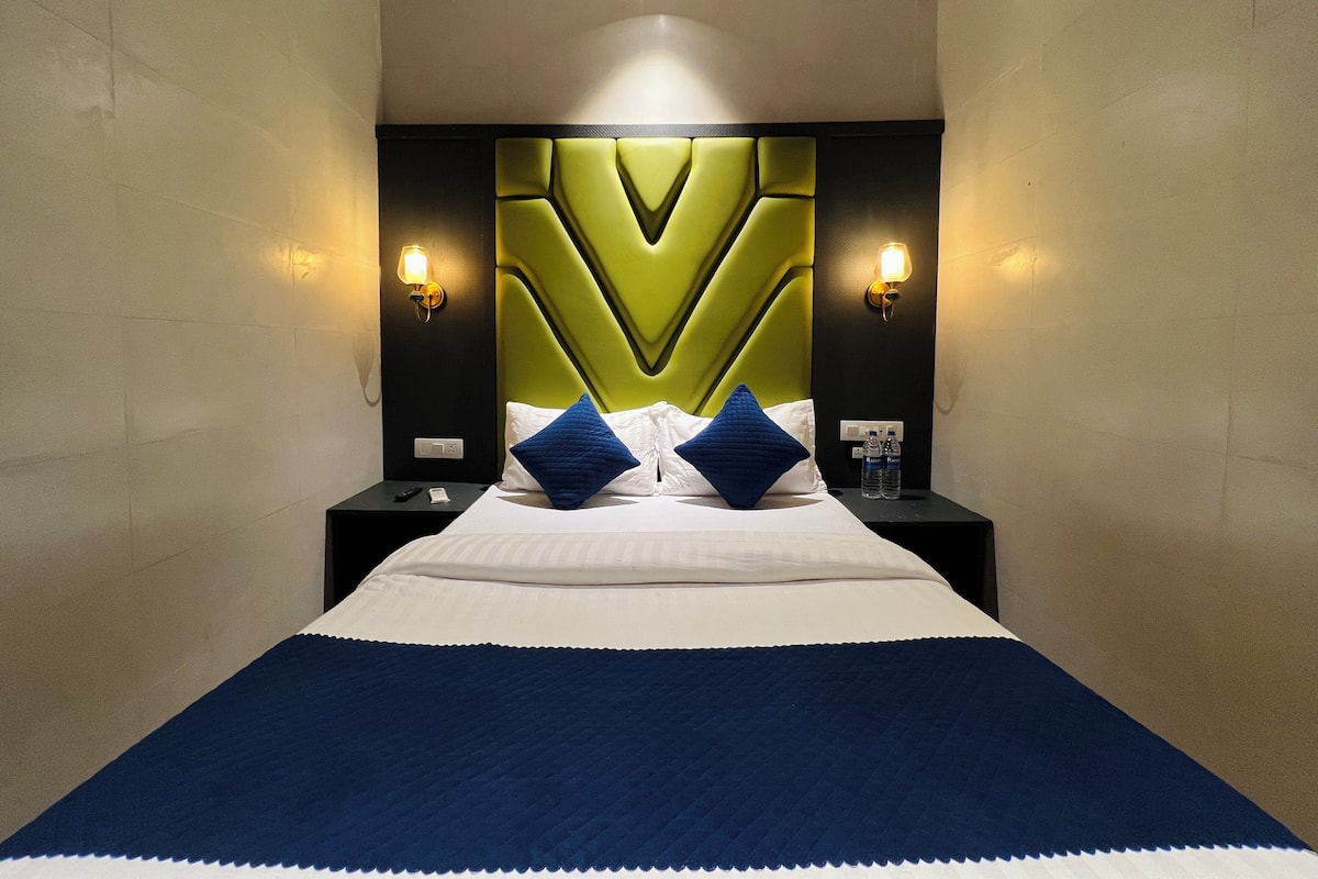 A hotel room with a large bed, two nightstands, a modern headboard, and wall-mounted lights.