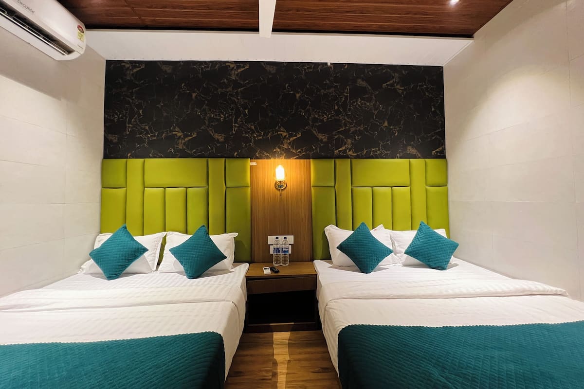 A hotel room with two beds, a green headboard, a marble-patterned wall, and a wooden ceiling.