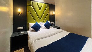 A hotel room with a bed, two bedside tables, a wall-mounted air conditioner, and two wall sconces. - Hotel Imperial Suite (Mumbai)