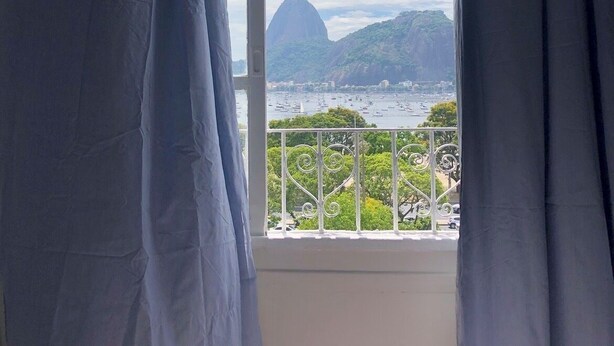 Une chambre avec une fenêtre donnant sur la côte, offrant une vue sur une montagne imposante et une marina.