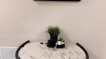 A round table with a marble top, black metal chairs, a framed quote on the wall, a small potted plant, and a decorative item on the table.