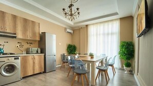 Eine moderne Küche mit Holzausstattung, einer Waschmaschine und einer Essecke mit Tisch und Stühlen.