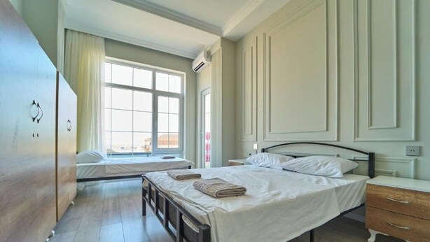 Ein Schlafzimmer mit einem großen Bett, einem kleineren Bett, einem Kleiderschrank und einem Fenster mit Vorhängen.
