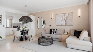 A modern living room with a sofa, a coffee table, and a dining area with chairs and a table. - Luxe 2BR Penthouse | 55m² rooftop – Sea/Pool Views (Estepona)