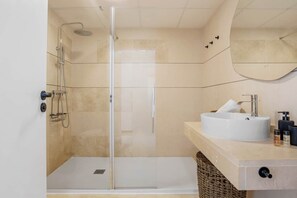 A modern bathroom with a glass-enclosed shower, a white sink with a round basin, and a mirror above the sink. - Luxe 2BR Penthouse | 55m² rooftop – Sea/Pool Views (Estepona)