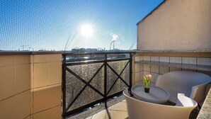 A balcony with a view of the city, a small table with a plant, and a chair.