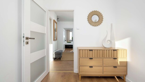 A hallway with a wooden dresser, a mirror, and a wall-mounted decorative piece.