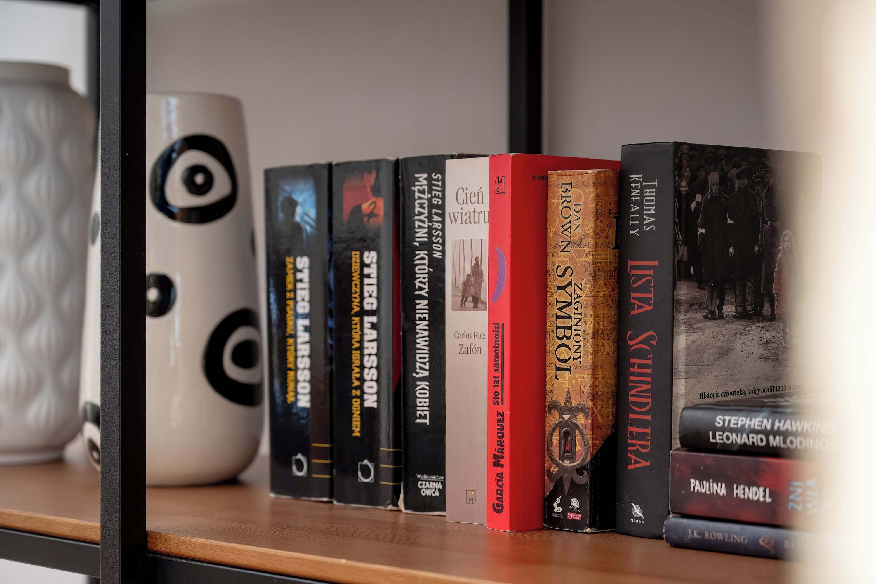 Una estantería con varios libros y una taza decorativa.