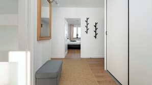 A hallway with a bench, a mirror, and two wall-mounted decorations.