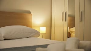 Ein Hotelzimmer mit Bett, Nachttisch, Lampe und Kleiderschrank.