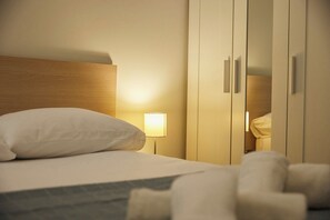 Ein Hotelzimmer mit Bett, Nachttisch, Lampe und Kleiderschrank.