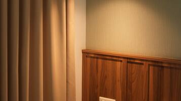 Una habitación con pared de paneles de madera, una lámpara colgante y una cama con almohada blanca.