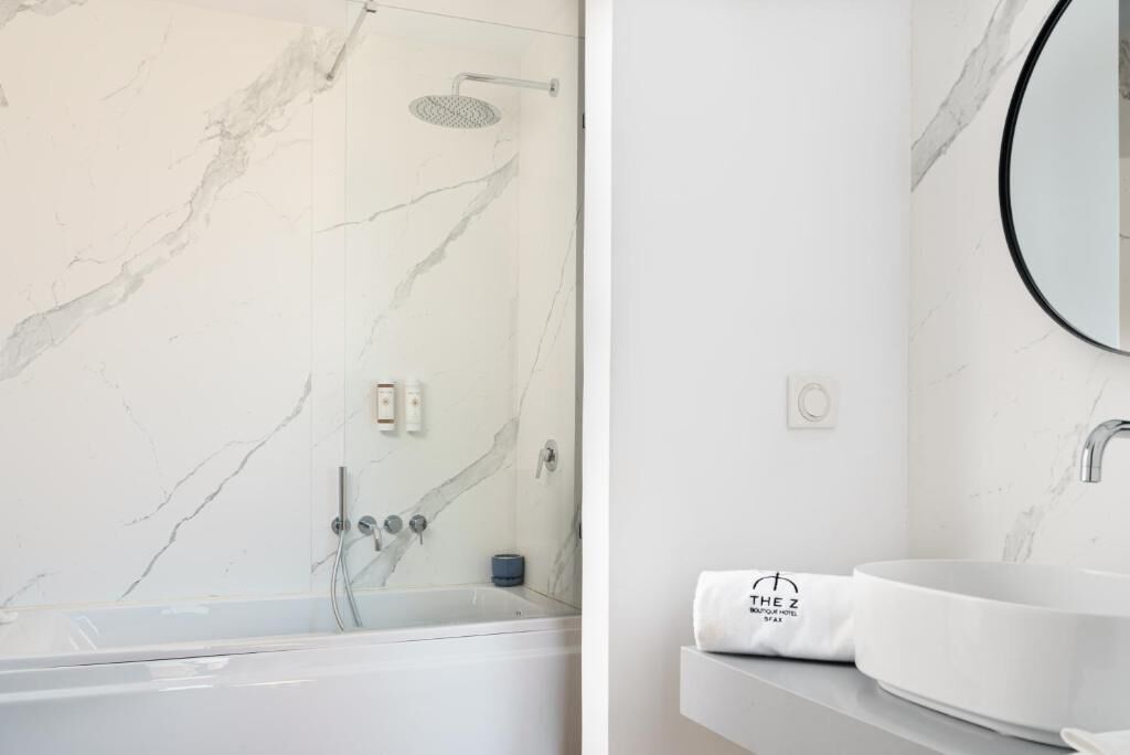 Un baño con bañera, ducha y lavabo con espejo.