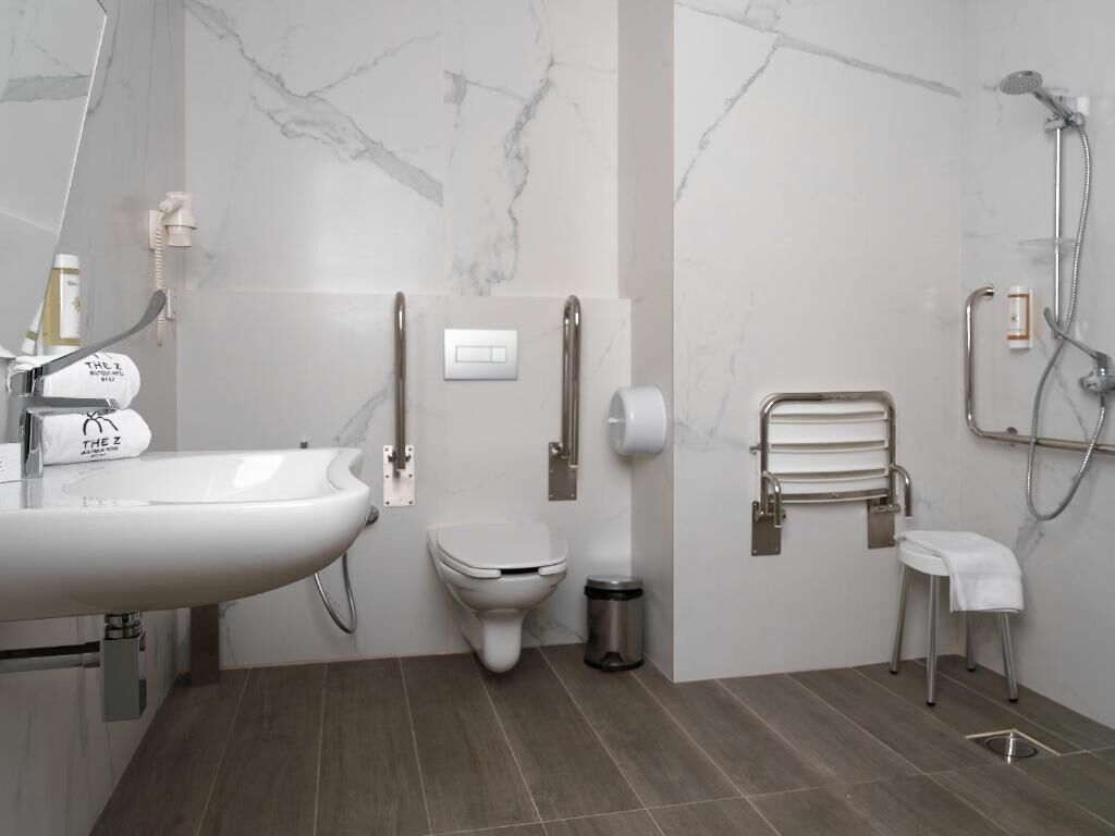 A modern bathroom with a white sink, toilet, and shower area.
