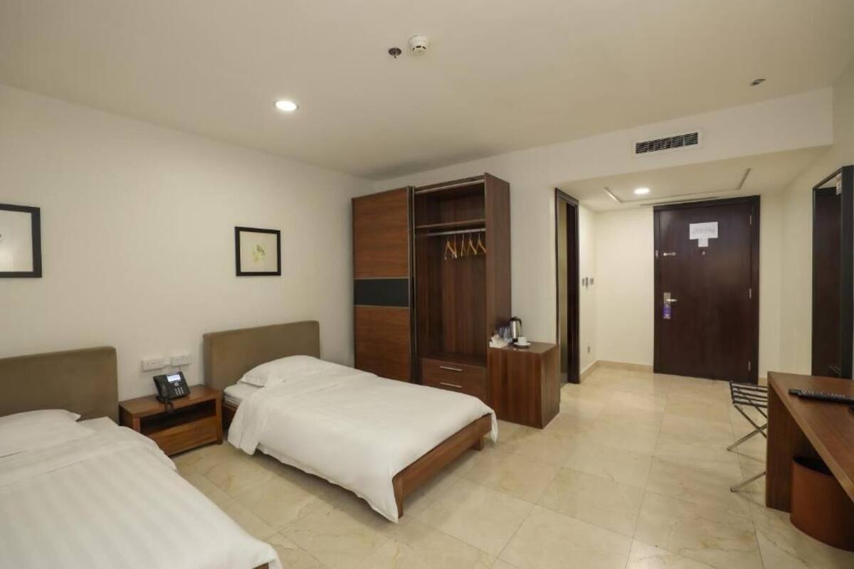 Une chambre d’hôtel avec deux lits, une armoire, un bureau et une chaise.
