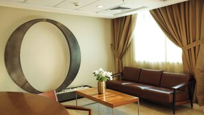 Ein modernes Wohnzimmer mit einer großen, runden Wanddekoration, einem braunen Ledersofa, einem Holztisch mit einer Vase voller weißer Blumen und einem Essbereich mit einem runden Tisch.