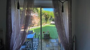A room with a sliding glass door leading to a patio with a lawn and a table. - Charming Cottage Overlooking River & Nr Town /FREE Parking (Maidstone)