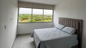 A bedroom with a large window, a bed with a headboard, and a ceiling fan. - Bright and Comfortable 2 Bedroom Apartment in Serena del Mar Cartagena (Cartagena)