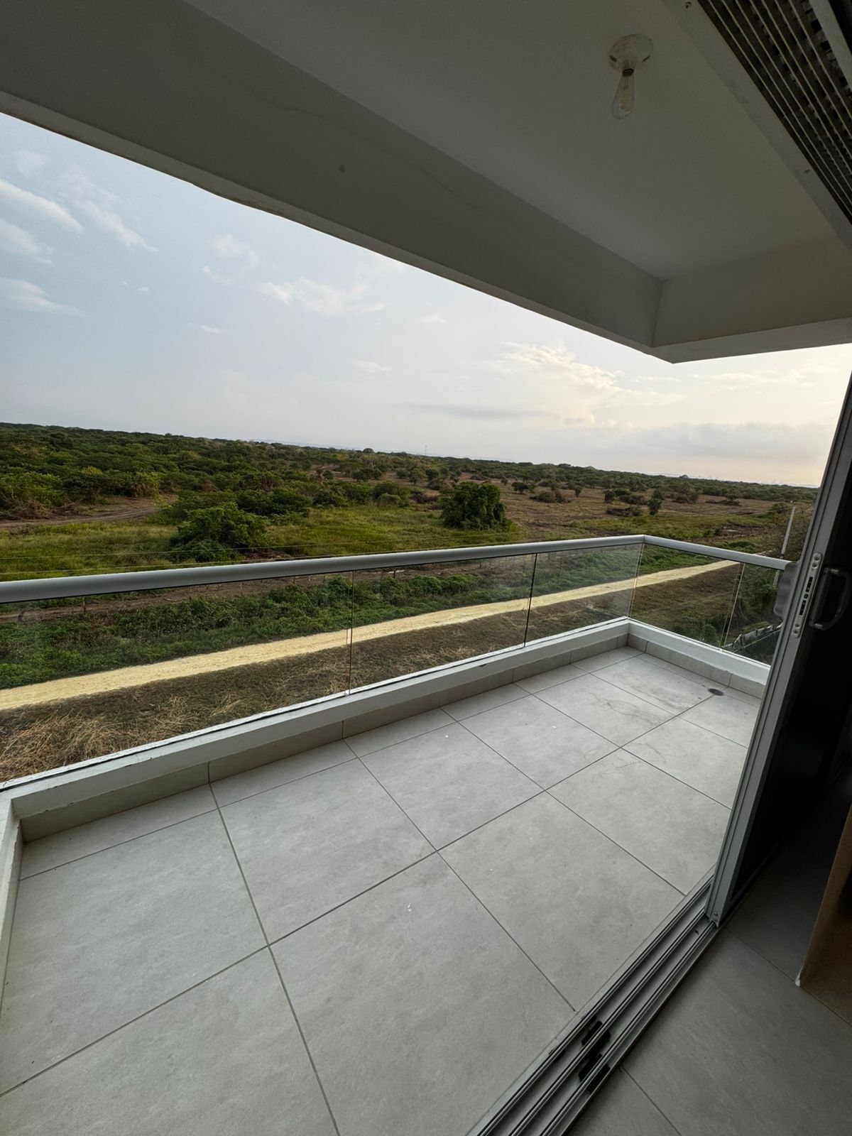 Ein Balkon mit Blick auf eine grüne Landschaft und einen Feldweg.