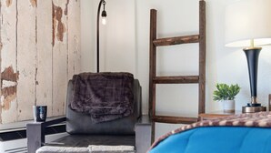 A room with a grey armchair, a wooden ladder, a lamp, and a small potted plant. - Driftwood Den – Condo for 2 (Kimberling City)