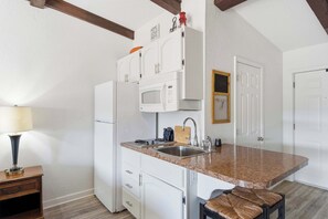 Una cocina compacta con armarios blancos, un microondas y un lavabo.