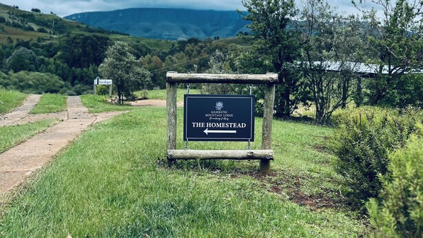 Segnaletica per 'The Homestead' al GAMBATHI MOUNTAIN LODGE, che indica un ambiente rurale e naturale con un sentiero sterrato che conduce al lodge.