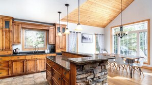 A spacious kitchen with wooden cabinets, a granite island, and a dining area with a table and chairs.