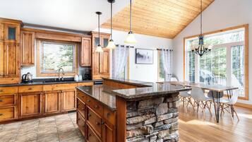 A spacious kitchen with wooden cabinets, a granite island, and a dining area with a table and chairs.
