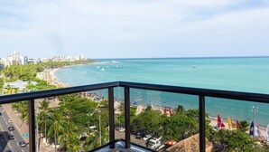 Een balkon met uitzicht op een strand, de oceaan en een stadsbeeld.