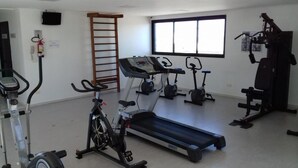 Een sportschool met loopbanden, elliptische trainers en een hometrainer.