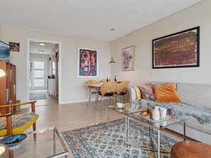 Ein modernes Wohnzimmer mit Sofa, Couchtisch und einem Essbereich mit Stühlen.
