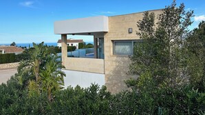 Un edificio moderno con tejado plano, grandes ventanales y vistas al mar.