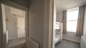 A bedroom with a bunk bed, a radiator, a door, and a window with curtains. - The Southport Two-Bed @ Stay Victoria Suites (Merseyside)
