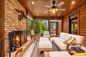 A cozy log cabin interior with a fireplace, seating area, and a view of the outdoors.