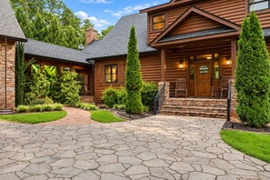 A log cabin with a stone-paved entrance, a covered porch, and a well-maintained garden.
