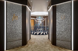 A hallway with textured walls, a patterned carpet, and a central elevator with a circular design.