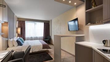 Una habitación de hotel moderna con cama, escritorio y kitchenette.