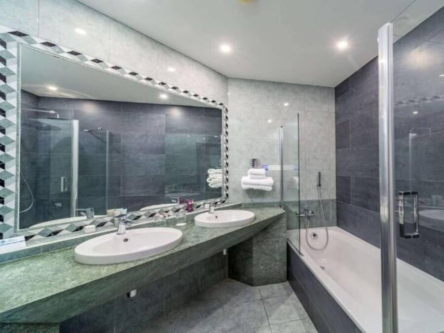 Ein modernes Badezimmer mit zwei Waschbecken, einem großen Spiegel und einer Duschkabine.