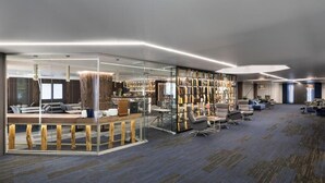 Rebedor modern d'hotel amb una separació de vidre, zona de seients i una presentació de llibres i objectes decoratius.